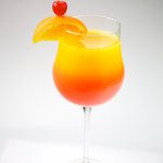 Tequila Sunrise garnished with orange and cherry, shot on a white background.